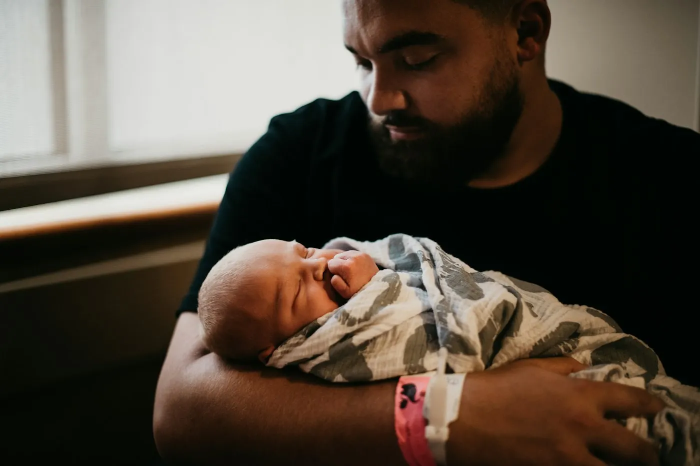 A father holding his sleeping newborn in the hospital
